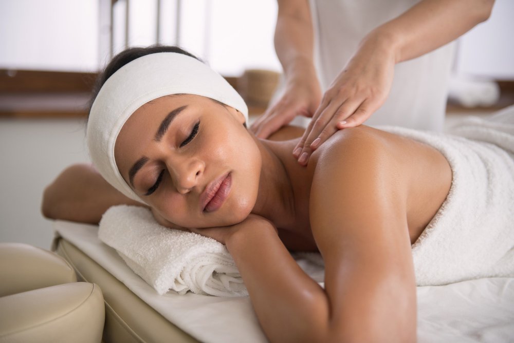 A person lying face down on a massage table with a therapist's hands gently applying pressure to their back.