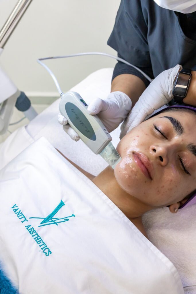 A woman relaxes with a red light therapy mask covering her face, showcasing a popular facial beauty treatment for skin rejuvenation.