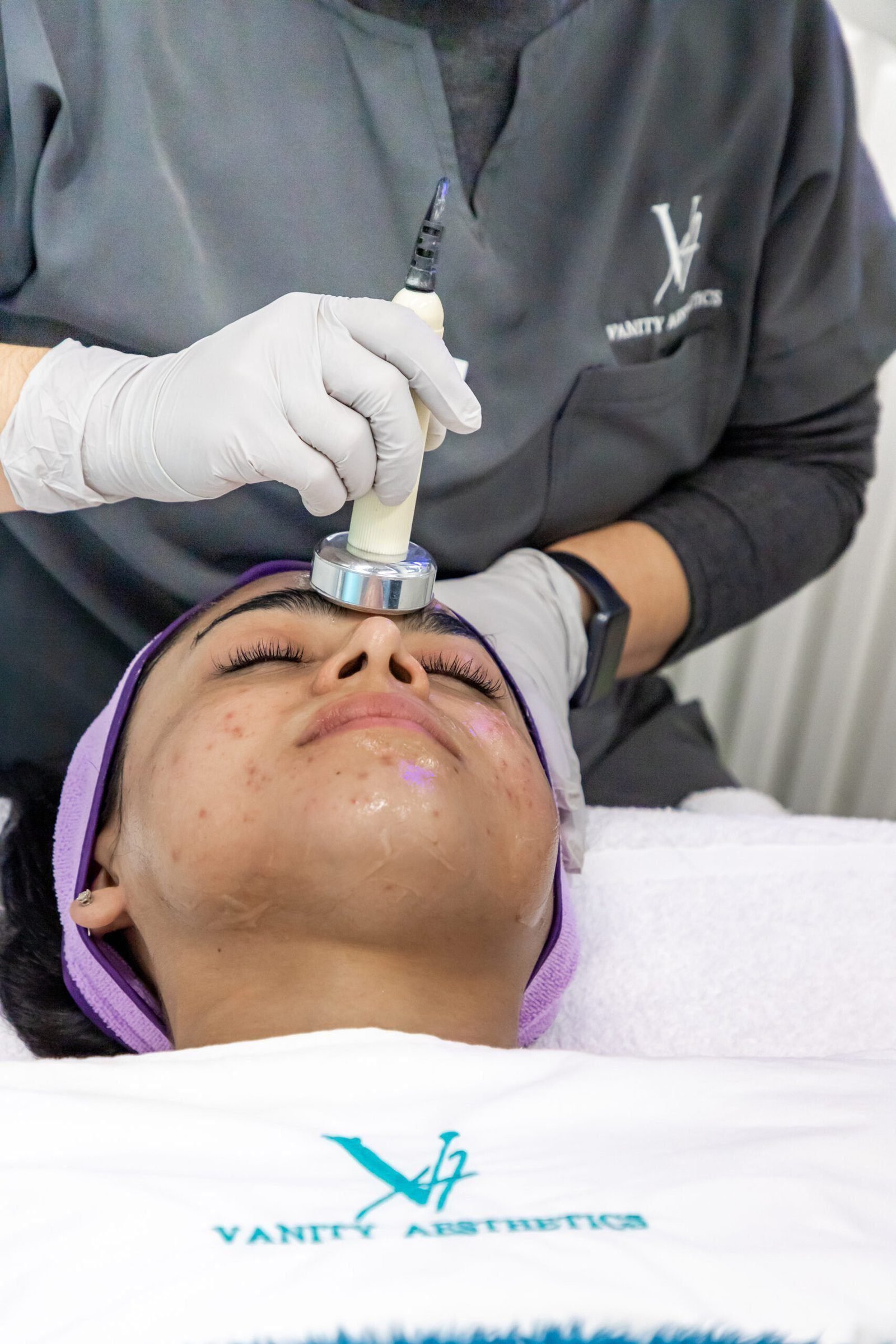 A close-up of a person receiving a facial treatment with a handheld device at Vanitya Aesthetics.