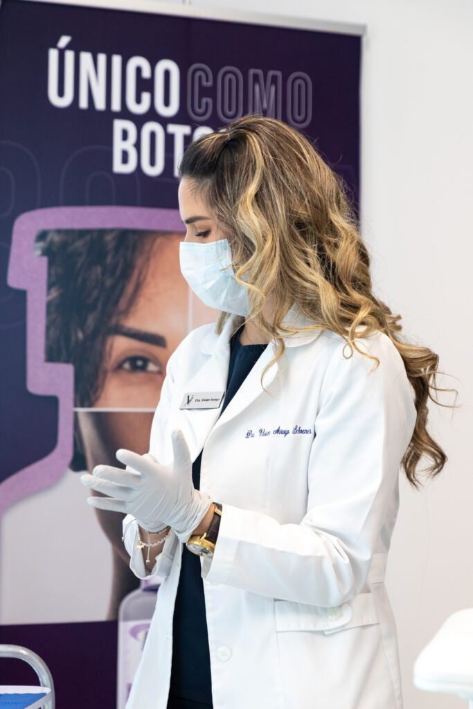 A woman smiling while receiving a Botox injection in her forehead at Vanitya Aesthetics.