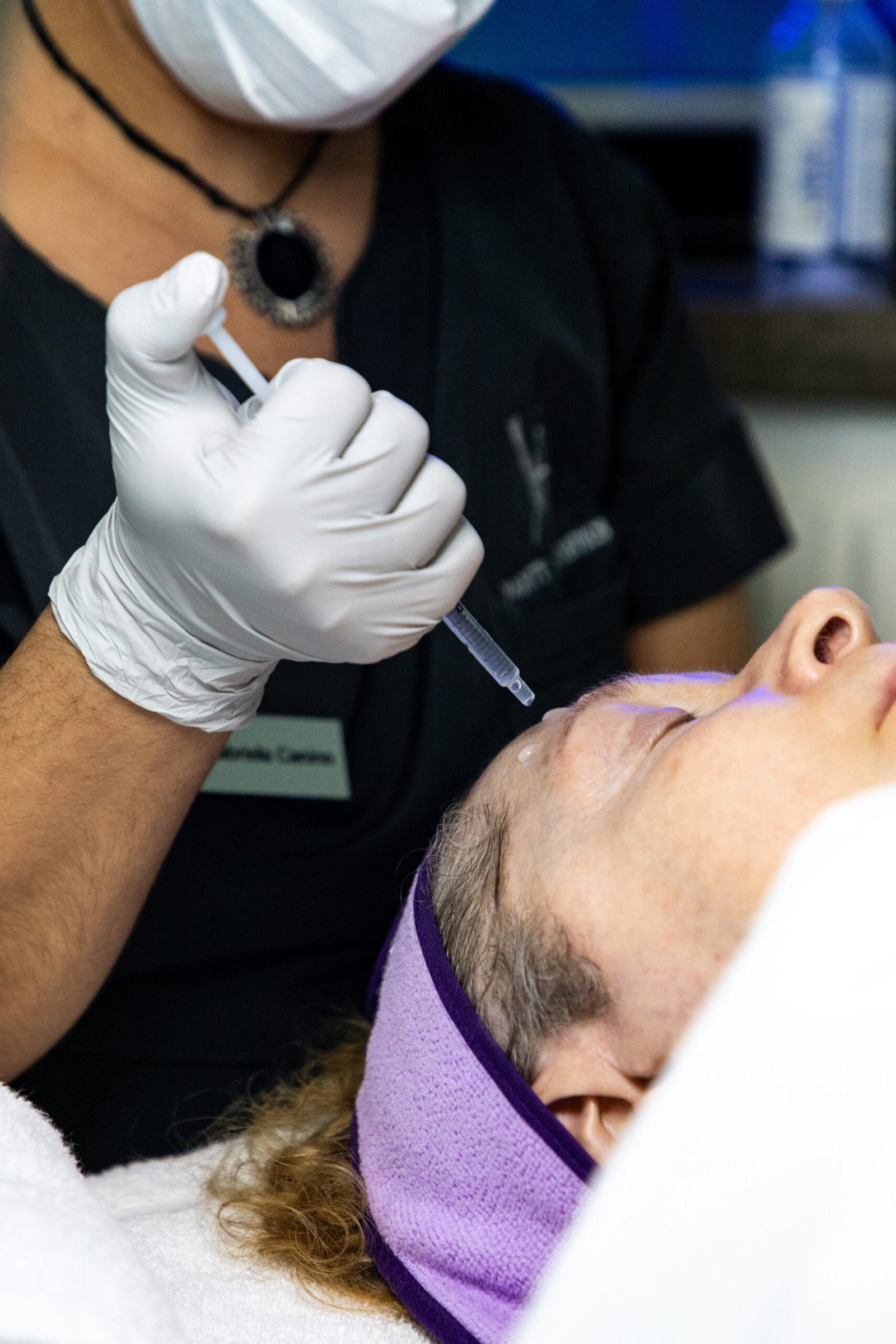 Close-up of a woman receiving a red light therapy facial, highlighting the application of the mask and the soothing red glow that promotes skin rejuvenation