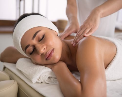 A person lying face down on a massage table with a therapist's hands gently applying pressure to their back.