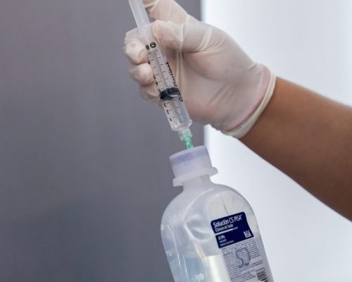 A smiling patient receives a Myers Cocktail IV drip in a serene treatment room at Vanity Aesthetics in Cancun.