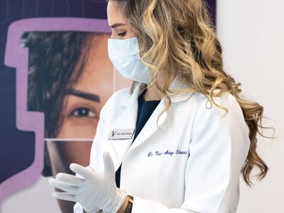 A woman smiling while receiving a Botox injection in her forehead at Vanitya Aesthetics.