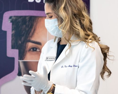 A woman smiling while receiving a Botox injection in her forehead at Vanitya Aesthetics.