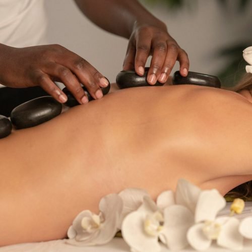 A person lying face down on a massage table with a therapist's hands gently applying pressure to their back.